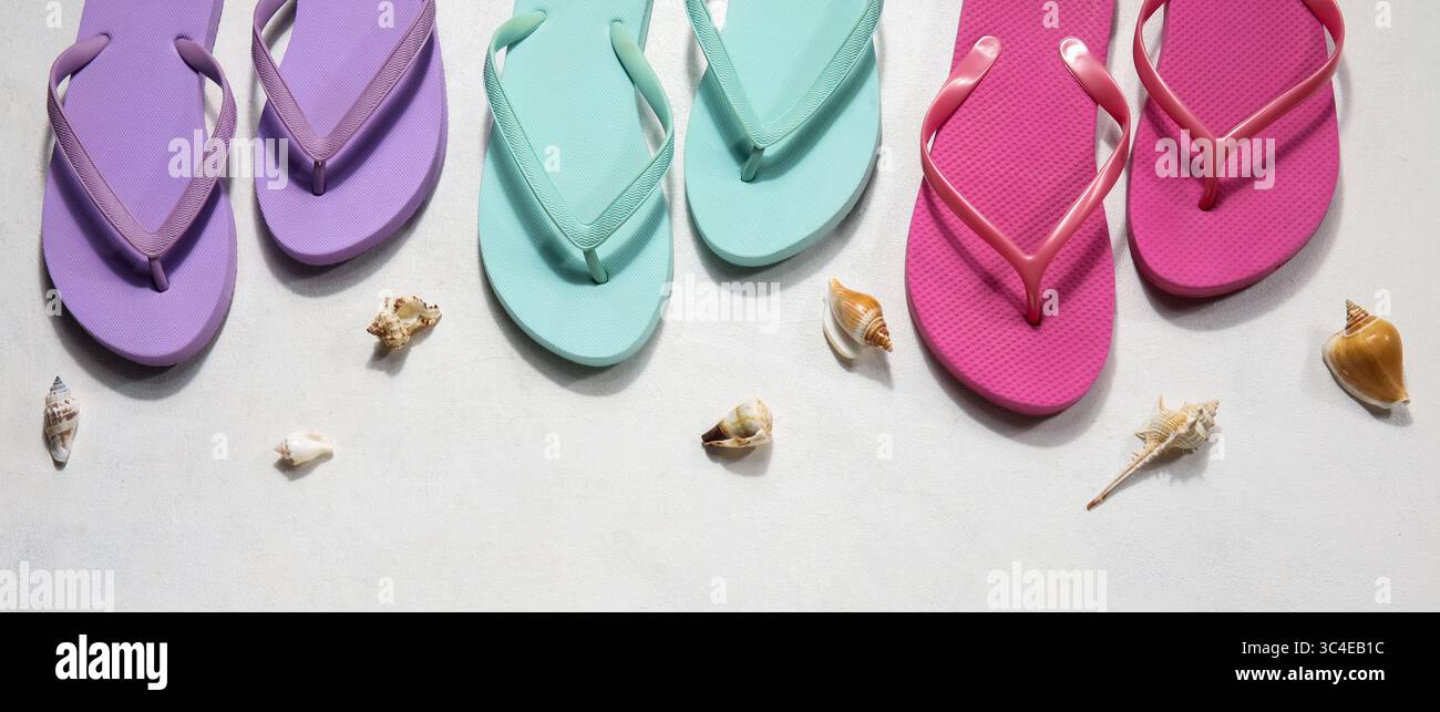 Colorful flip flops with seashells on light background, top view Stock Photo
