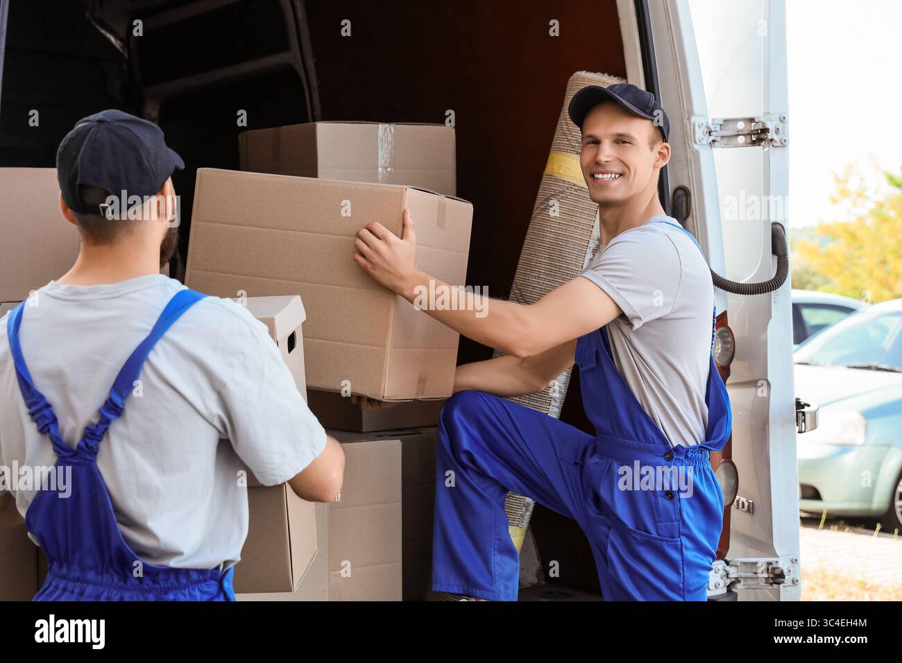 Male movers unloading boxes from car outdoors Stock Photo