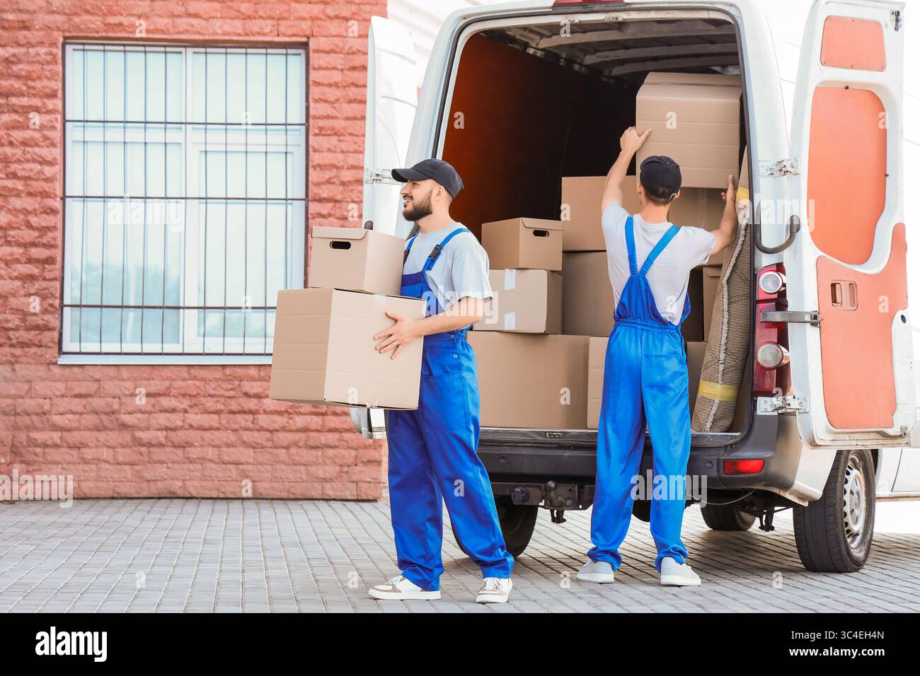 Male movers unloading boxes outdoors Stock Photo