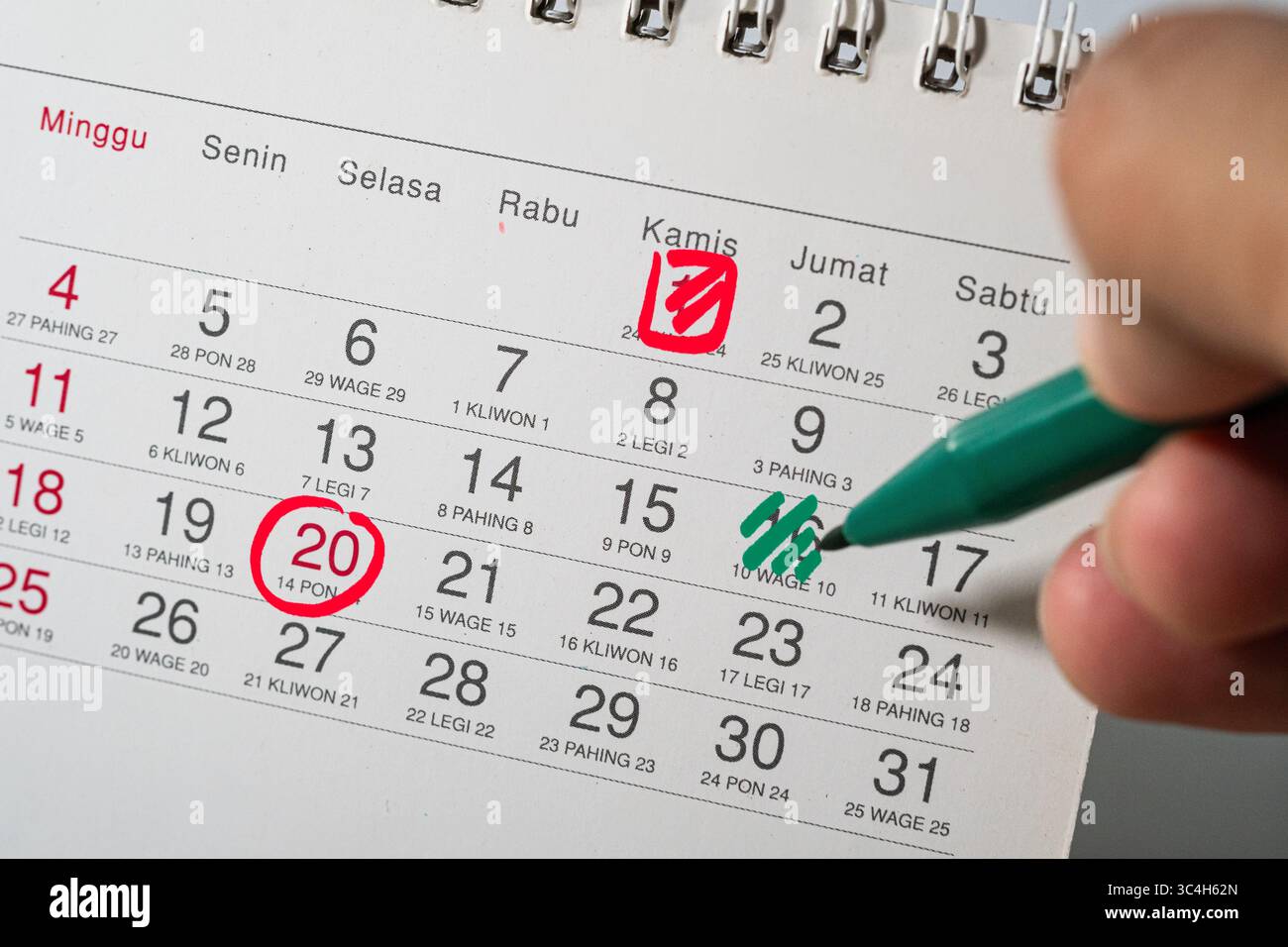 Hand holding green marker marking important dates on a box-style ...
