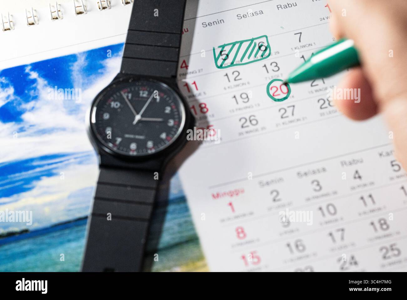 Hand holding green marker marking important dates on a calendar. Ideal ...