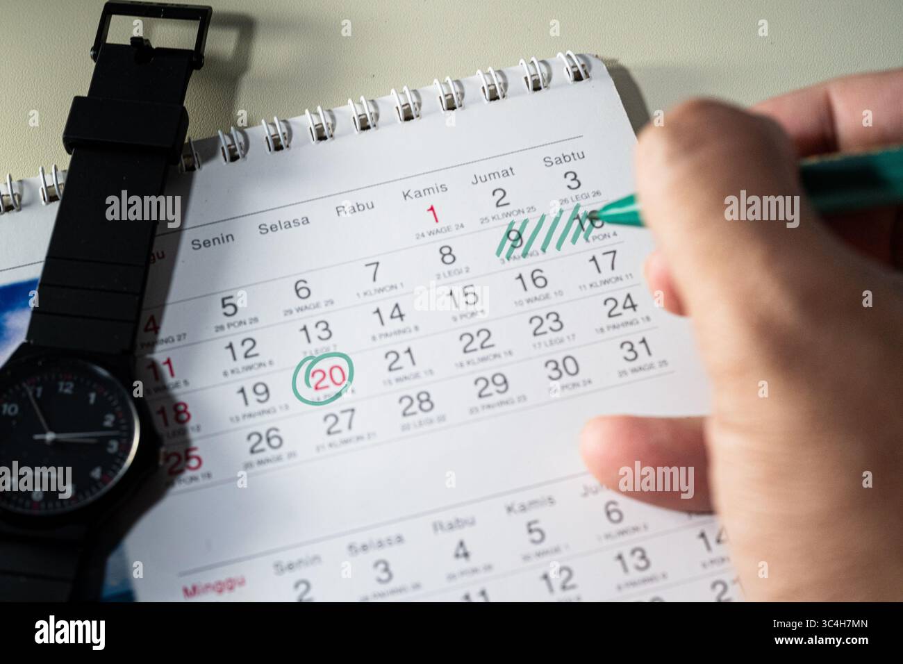 Hand holding green marker marking important dates on a calendar. Ideal ...