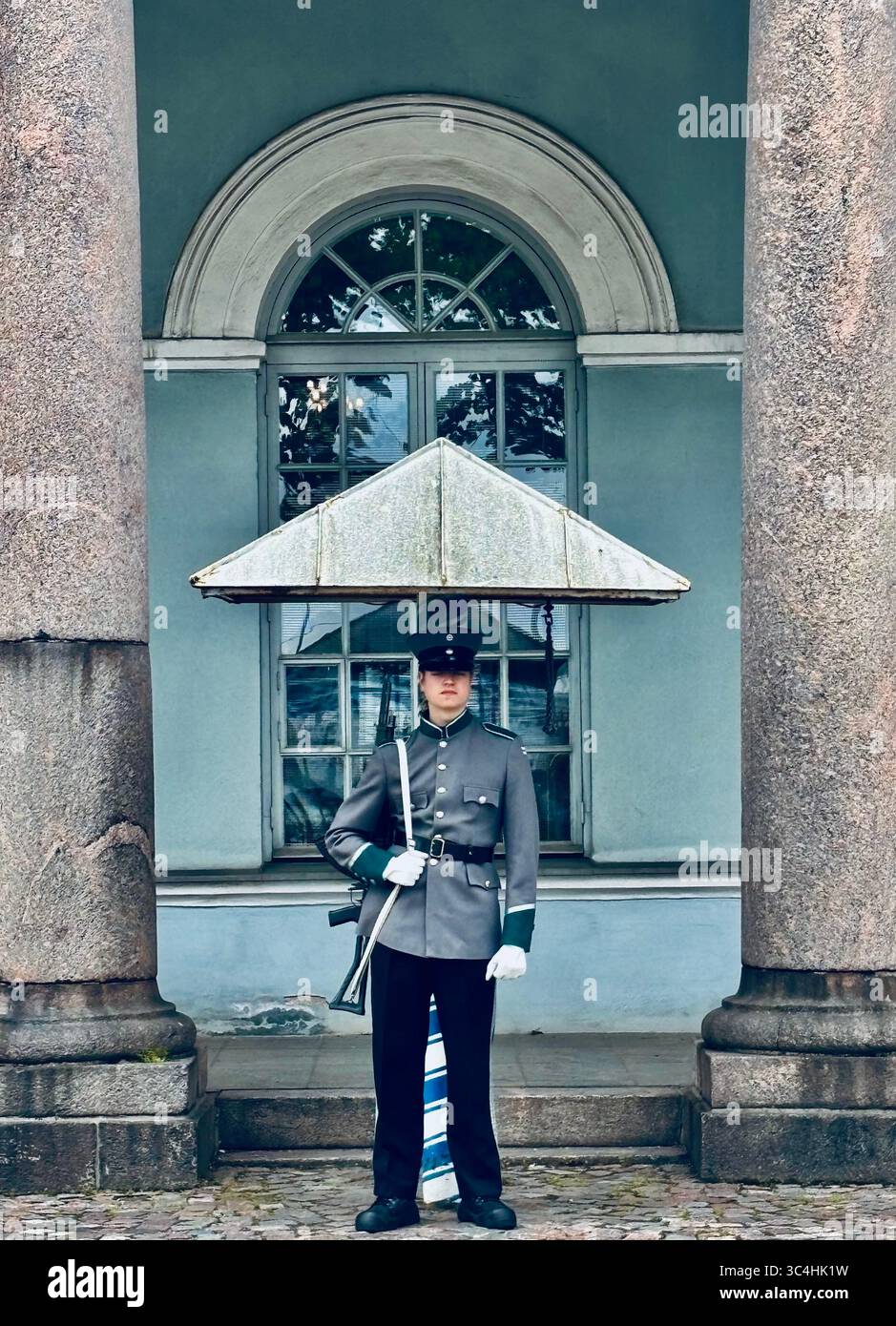 A guard standng outside the house of the Main Guard situated next to the Presidential Palace in Helsinki, Finland - Smartphone Captured Stock Image