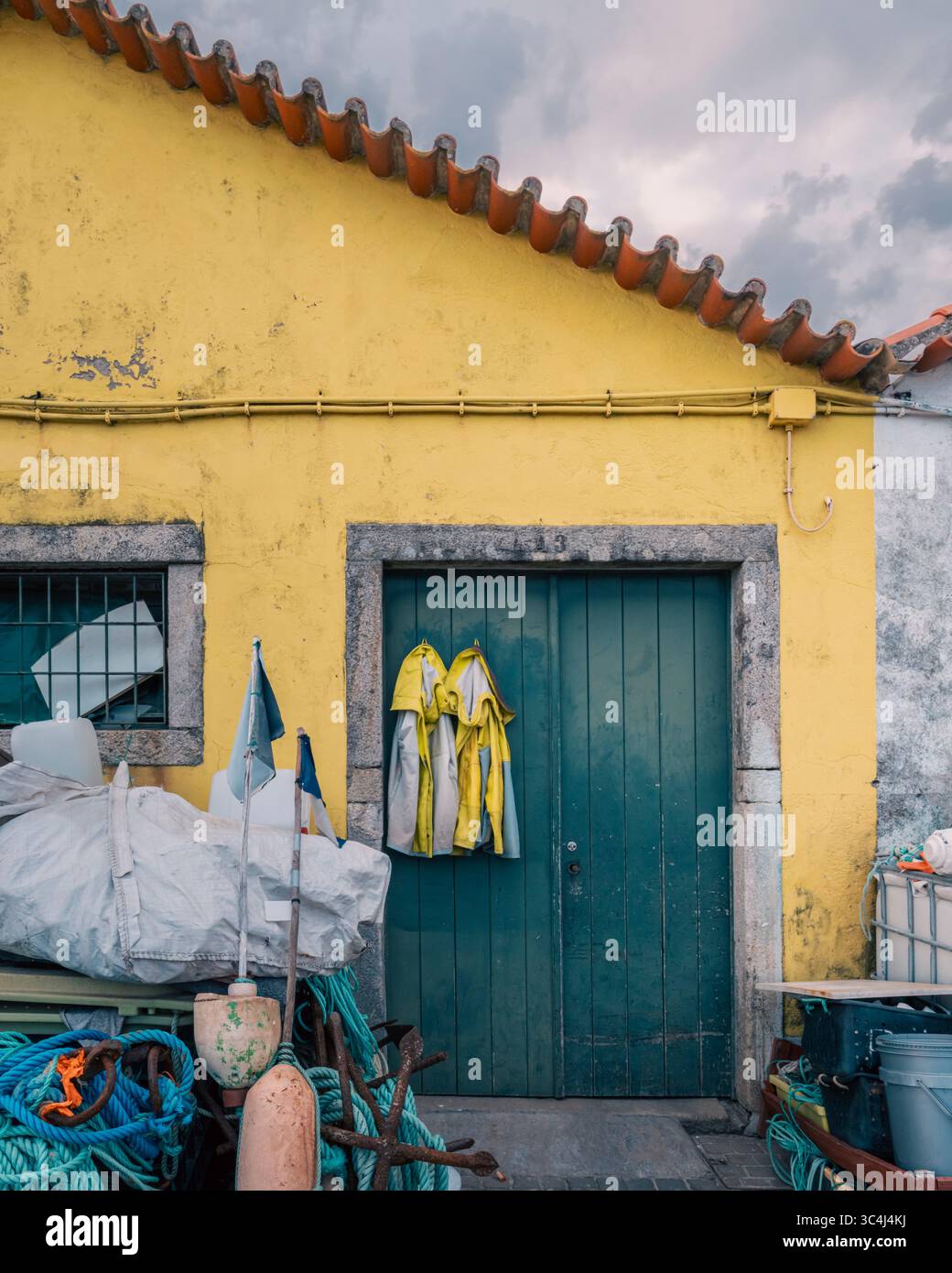 Traditional Portuguese Fishing House With Yellow Raincoats And Equipment In Coastal Village. Maritime Heritage, Fisherman Storage, Northern Portugal S Stock Photo