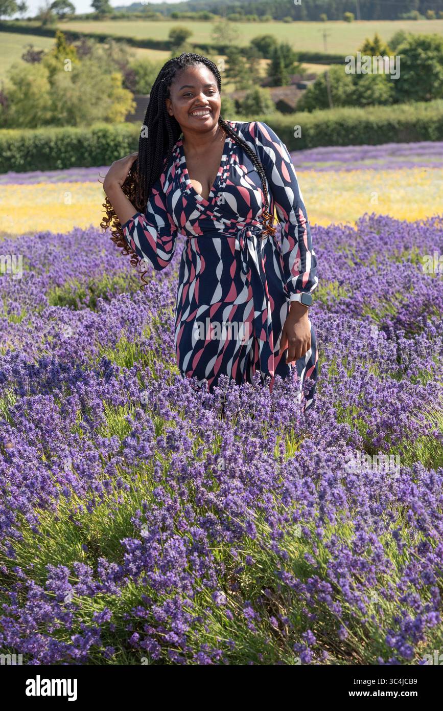 Gloucestershire England UK. 30.06. 2025. African woman posing for a portrait in a field of lavender UK. Stock Photo