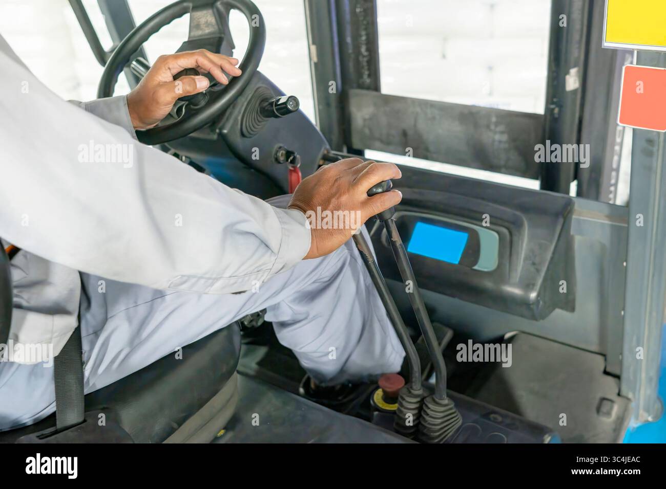 Worker operator controls a forklift inside a warehouse. Storage, inventory, industry, and logistics Stock Photo
