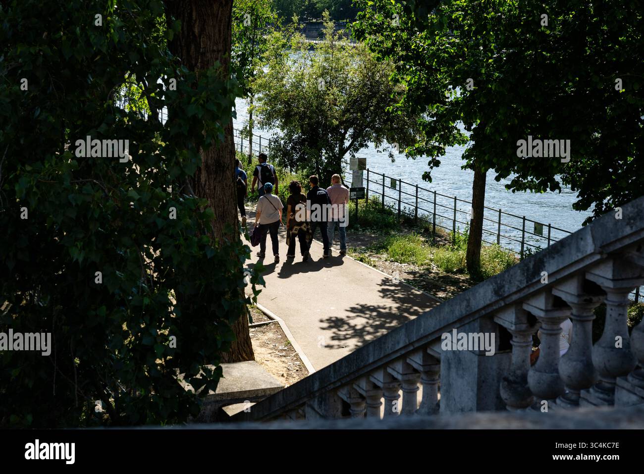 People walking along Seine riverside path with trees and railings Paris ...