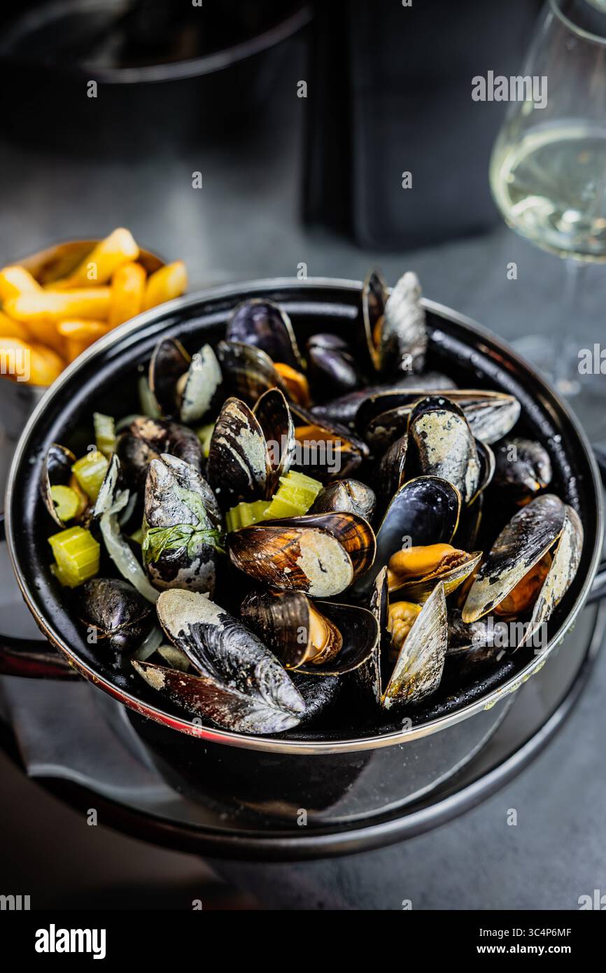 French fries and mussels in a pot - traditional serving of mussels in Belgian restaurants Stock Photo