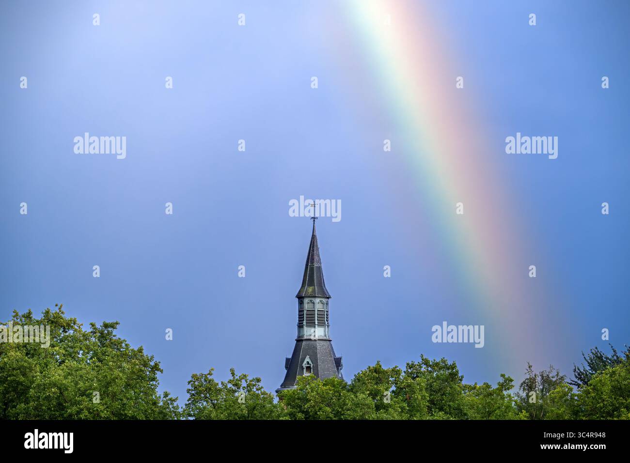 Colourful rainbow over trees and castle tower after downpour during thunderstorm in summer Stock Photo