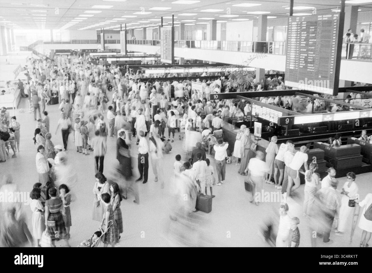 Holiday crowds Schiphol, Schiphol, Schiphol, 04-07-1986 Whizgle News, Dutch Desk, The Netherlands, 1950-2000 A bustling airport terminal filled with travelers of diverse backgrounds, some checking flight information while others are engaged in conversation or moving through the crowd. The scene captures the energy and activity of people navigating their journeys amidst a backdrop of departure and arrival boards. Stock Photo
