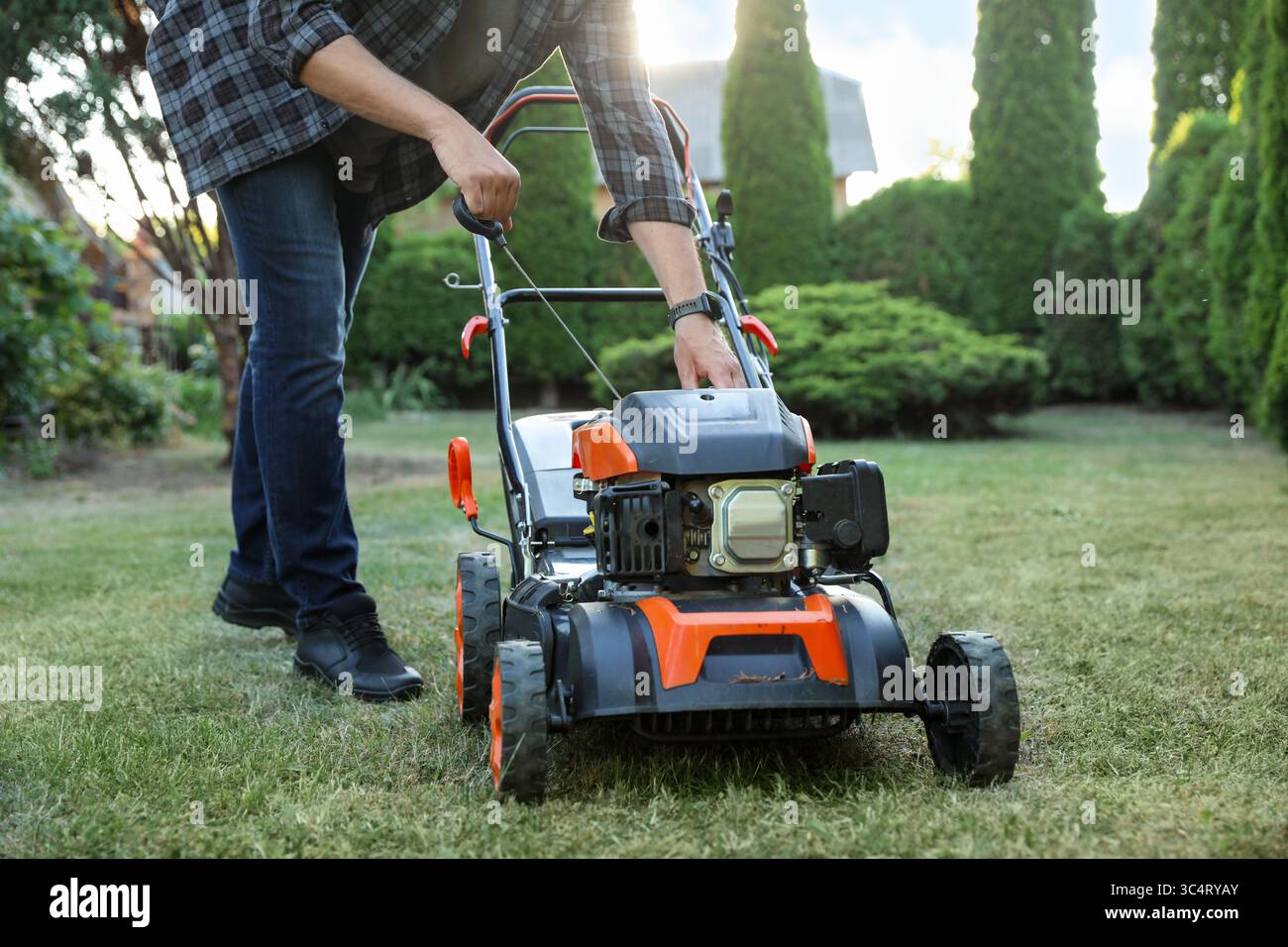 Gardener pulling lawnmower starter cord hi-res stock photography and