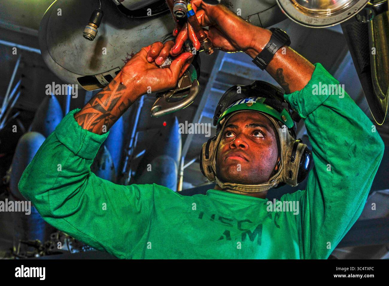 Sep 15, 2018 - Philippine Sea - Aviation Mechanic Airman Joel-Marc Lobban, from Kingsland, Jamaica, performs maintenance on an MH-60S Sea Hawk helicopter assigned to Helicopter Sea Combat Squadron (HSC) 12 in the hangar bay of Navy's forward-deployed aircraft carrier USS Ronald Reagan (CVN 76) in preparation for the Valiant Shield 2018 exercise. Valiant Shield is a U.S. only, biennial field training exercise (FTX) with a focus on integration of joint training in a blue-water environment among U.S. forces. This training enables real-world proficiency in sustaining joint forces through detecting Stock Photo