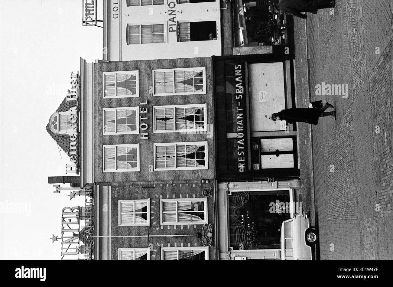 Hotel prominently displayed hi res - Hotel Restaurant Spanish Haarlem Grote Markt The Netherlands Whizgle News Dutch Desk The Netherlands 1950 2000 A Bustling Urban Scene Featuring A Distinct Building With A Restaurant Sign And Hotel Prominently Displayed The Establishment Is Complemented By Vintage Signage And A Passerby Navigating The Street Nearby Additional Signs Hint At A Lively Atmosphere With Vehicles Parked Along The Curb 3C4W4YF