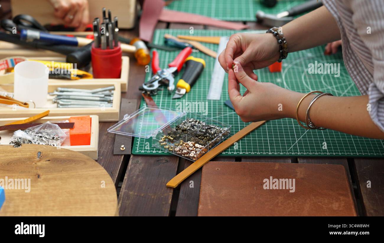Hands working with leather and metal crafting tools. Stock Photo