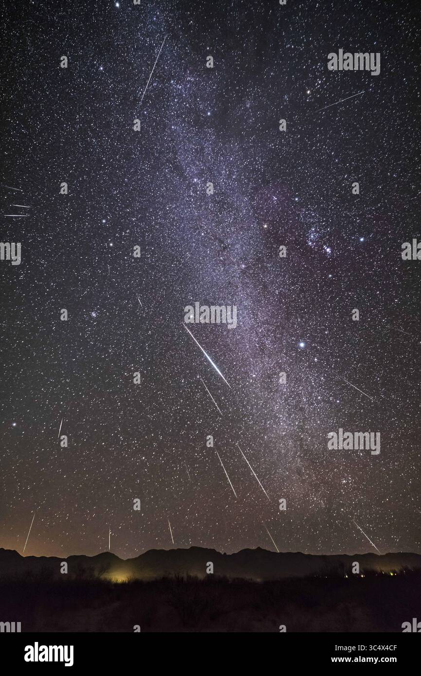 December 13, 2017 - Arizona, United States - The Geminid meteor shower of December 13, 2017 in a view framing the winter Milky Way from Auriga (at top) to Puppis (at bottom) with Gemini itself, the radiant of the shower at left, and Orion at right. ..The view is looking southeast to the Peloncillo Mountains in New Mexico though the site at Quailway Cottage is in Arizona, near Portal. ..This is a composite stack of one base image with the brightest meteor, then 20 other images layered in each with a meteor. The camera was not tracking the sky, so I rotated and moved each of the layered-in frame Stock Photo