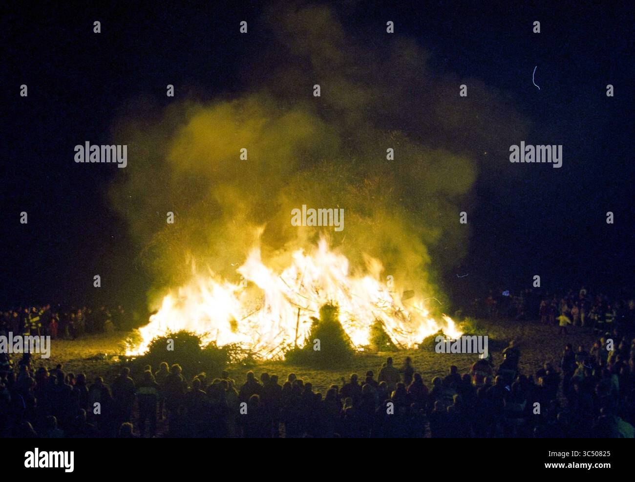 Christmas tree burning, Zandvoort, Zandvoort, 06-01-2004 Whizgle News, Dutch Desk, The Netherlands, 1950-2000 A large bonfire blazes brightly at the center of a gathering, with a crowd of people surrounding it, illuminated by the flickering flames against a dark background. The atmosphere is lively and festive, as sparks and smoke rise into the night sky. Stock Photo