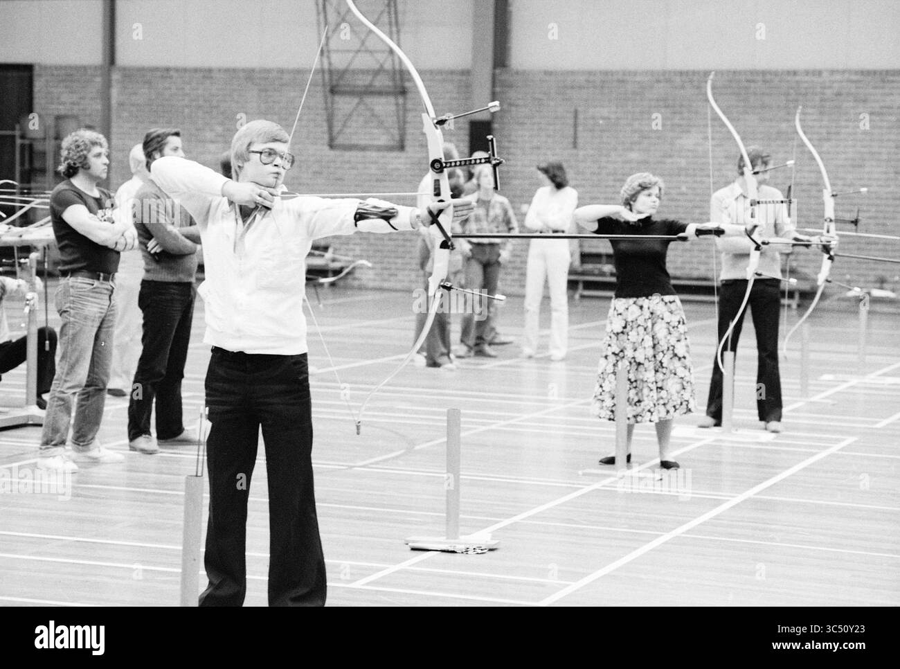 Archery Competitions in IJmuiden, Archery, IJmuiden, The Netherlands, 29-04-1979 Whizgle News, Dutch Desk, The Netherlands, 1950-2000 A group of archers focuses intently as they prepare to shoot, showcasing concentration and skill in a indoor training setting. Stock Photo