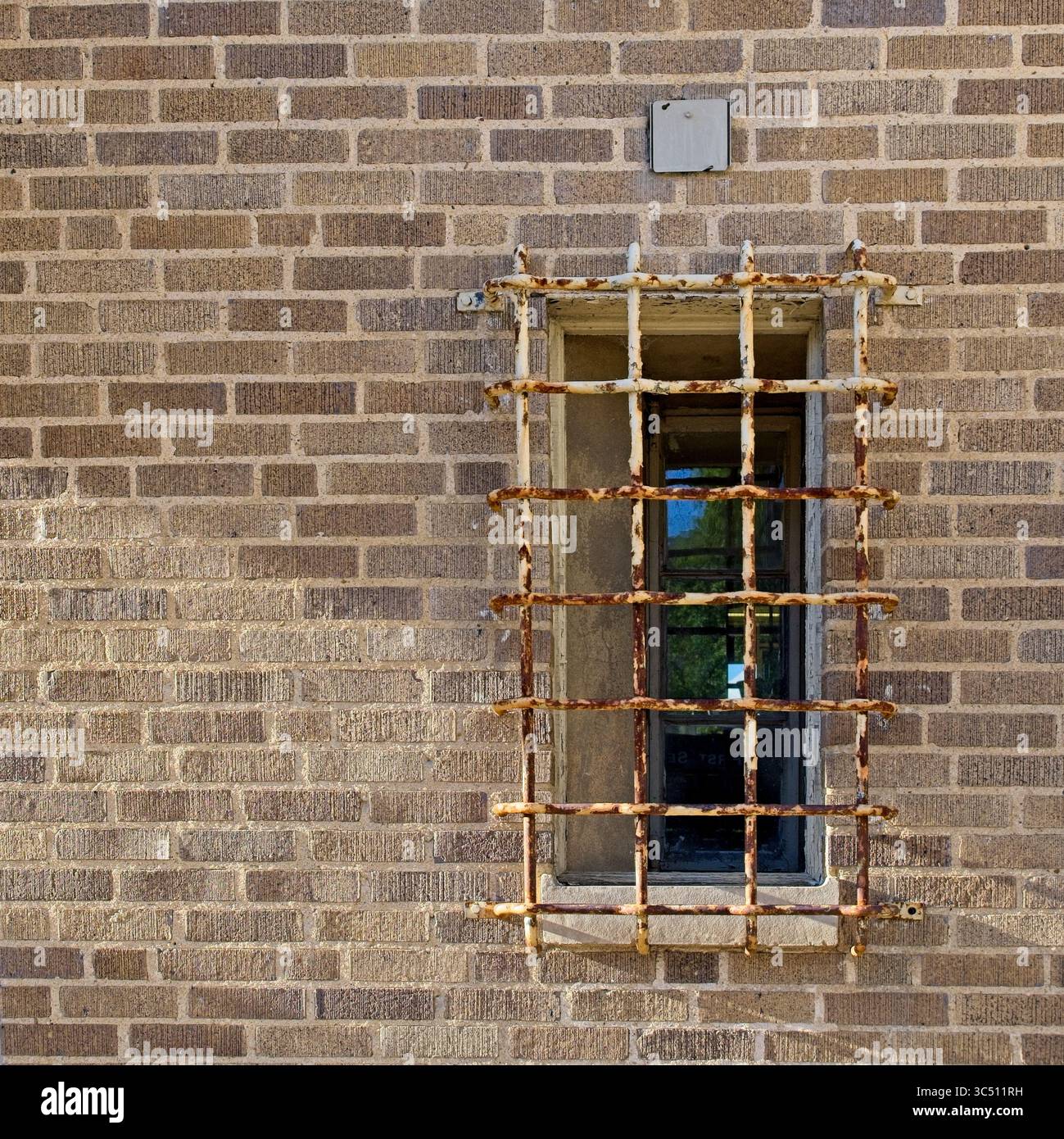 Rusty security bars around window to brick wall Stock Photo