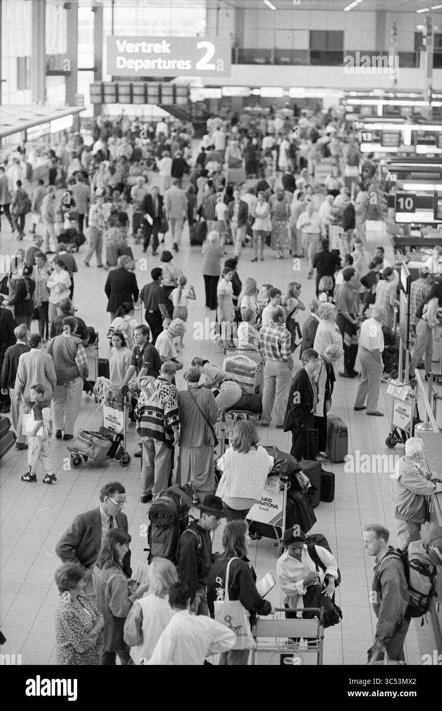 Busy in departure hall, Schiphol, Schiphol, 08-08-1996 Whizgle News, Dutch Desk, The Netherlands, 1950-2000 A bustling airport terminal filled with travelers, many carrying luggage and checking in for their flights. The atmosphere is lively as people interact and navigate the crowded space, illuminated by overhead signage indicating departures. Stock Photo
