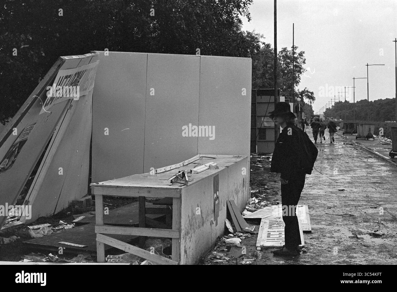 Holland Pop Festival in the Kralingse bos, which has gone down in history as the Dutch version of the American Woodstock festival. With performances by The Byrds, Mungo Jerry, Canned Heat and Jefferson Airplane, Music, Rotterdam, 26-06-1970 Whizgle News, Dutch Desk, The Netherlands, 1950-2000 A figure stands contemplatively near a toppled structure, surrounded by debris and remnants of a once-busy area. In the background, a few people navigate along a litter-strewn path, while trees and utility poles line the scene, hinting at the area's past vibrancy. Stock Photo