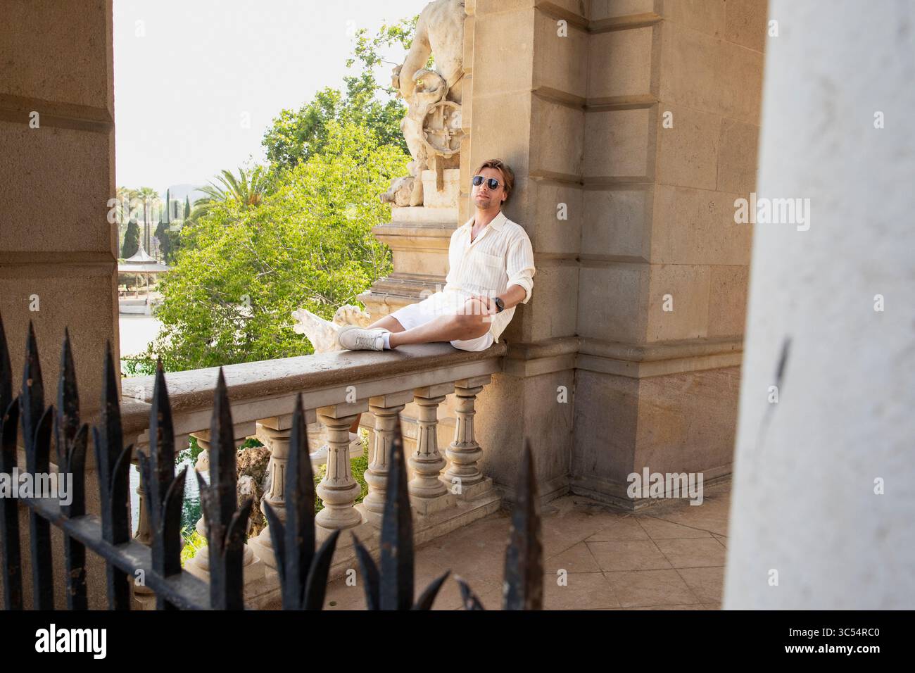Stone Railing Sitting Modern traveler sitting on stone railing with statues. Man in glasses ...