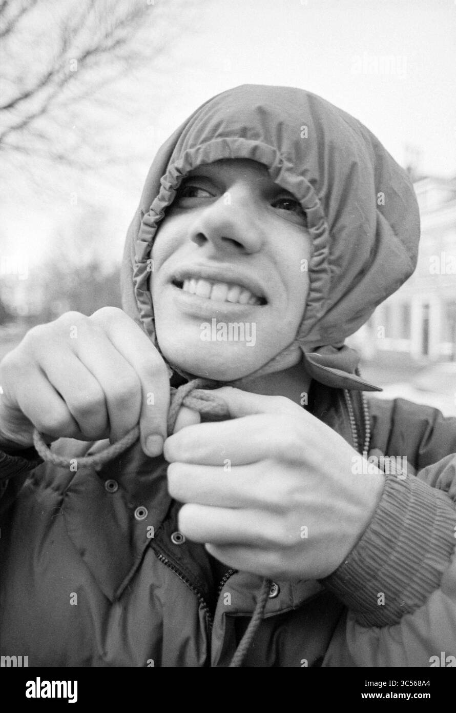 Portraits Frans and plaf, United photos, 01-03-1990 Whizgle News, Dutch Desk, The Netherlands, 1950-2000 A person smiles brightly as they adjust the drawstrings of a hooded jacket, creating a playful and lighthearted moment. The surrounding environment hints at a chilly day, enhancing the cheerful expression on their face. Stock Photo