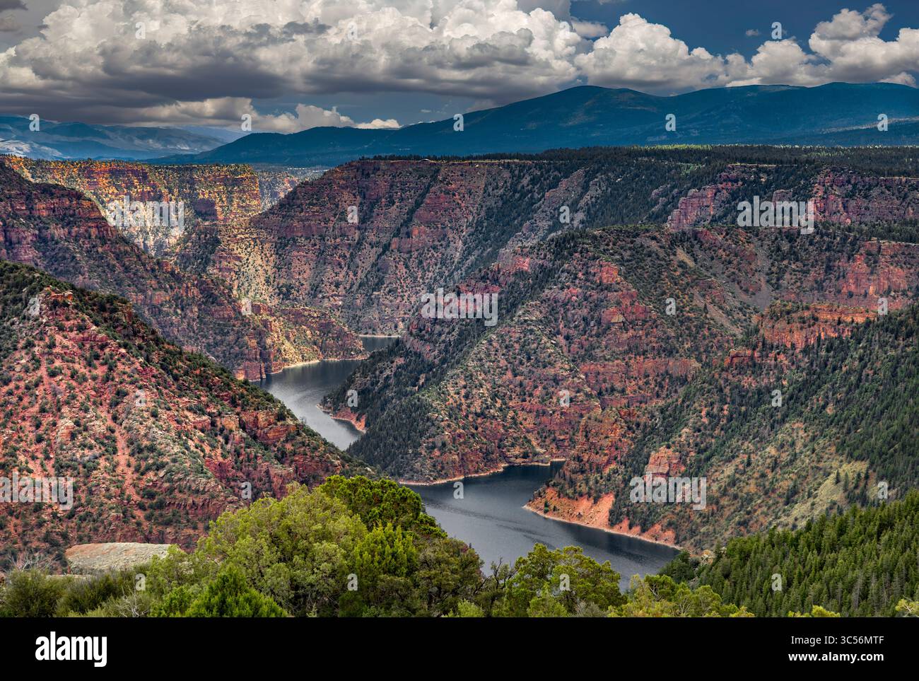 Vividly Banded Sedimentary Rock rises above the Blue Waters of Flaming Gorge Reservoir along the Utah-Wyoming border. Stock Photo