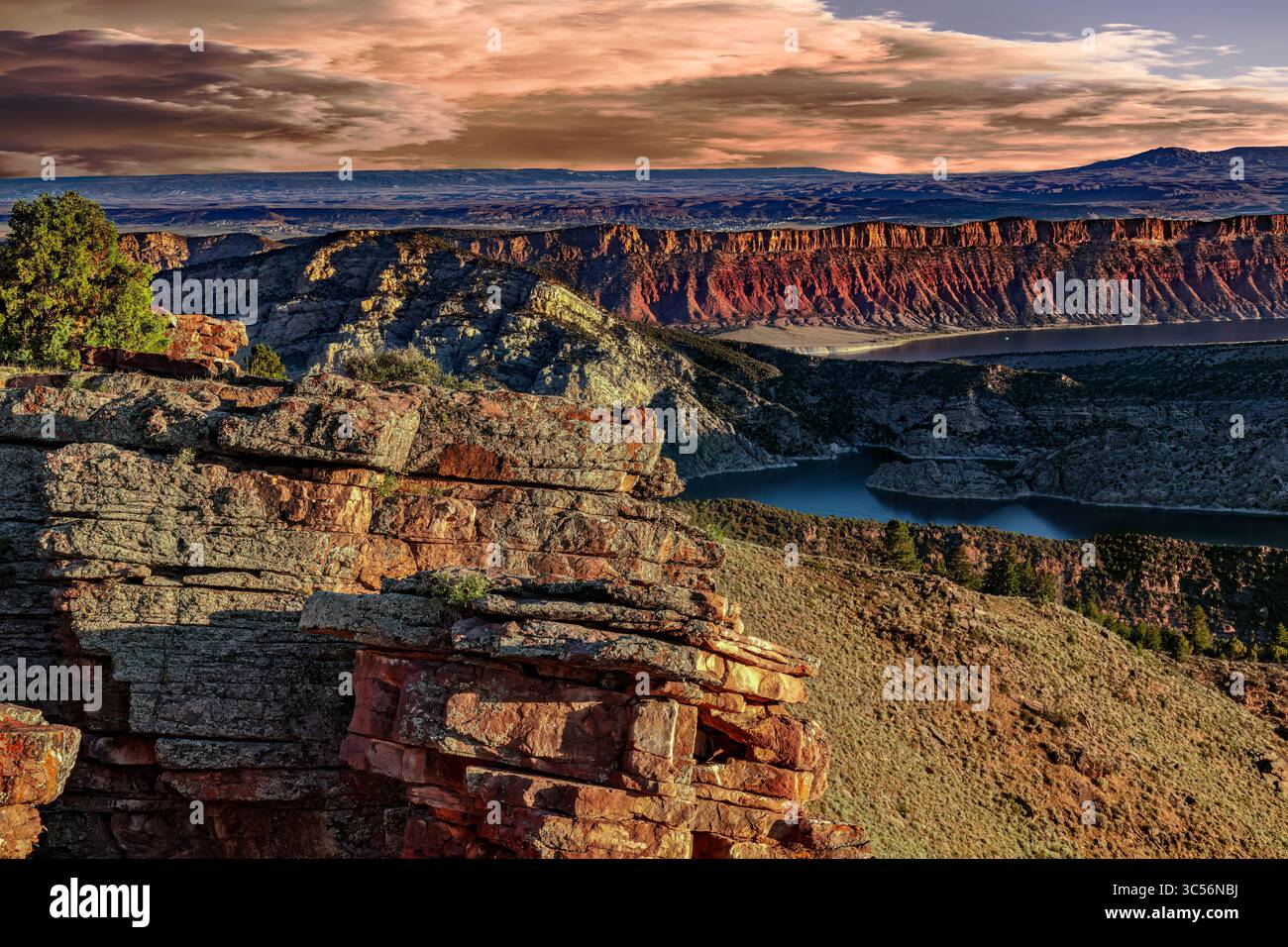 Vividly Banded Sedimentary Rock rises above the Blue Waters of Flaming Gorge Reservoir along the Utah-Wyoming border. Stock Photo