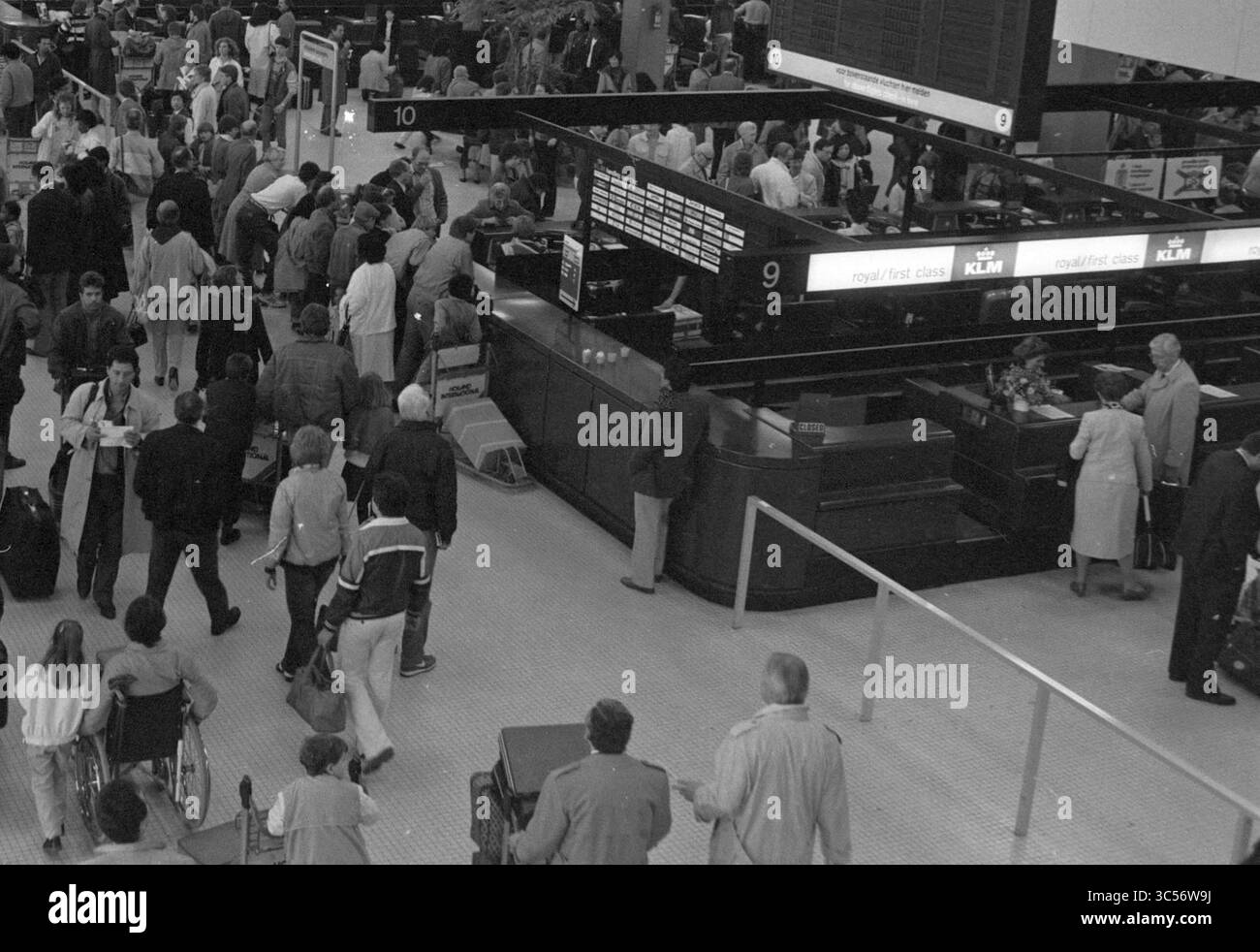 Huge crowds in the Schiphol departure hall due to the Easter holidays and air traffic controllers' strike., Schiphol, 05-04-1985 Whizgle News, Dutch Desk, The Netherlands, 1950-2000 A bustling airport check-in area filled with travelers. People are waiting in lines and moving about, with signs indicating different airline counters. The atmosphere is busy and dynamic, reflecting the hurried nature of air travel. Stock Photo