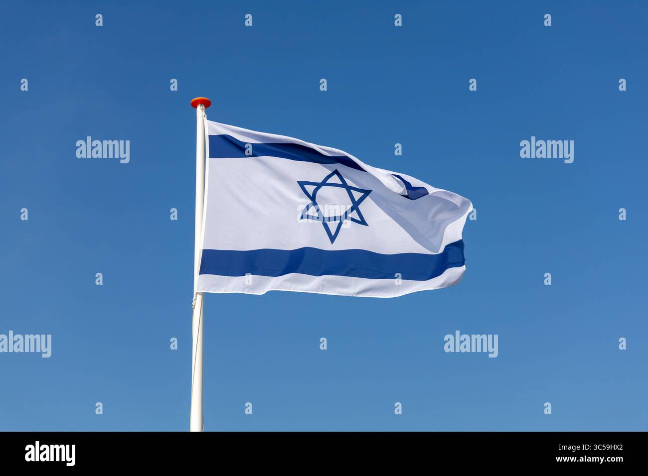 The national flag of Israel with its blue Star of David on a white background, waving against a clear blue sky. Stock Photo