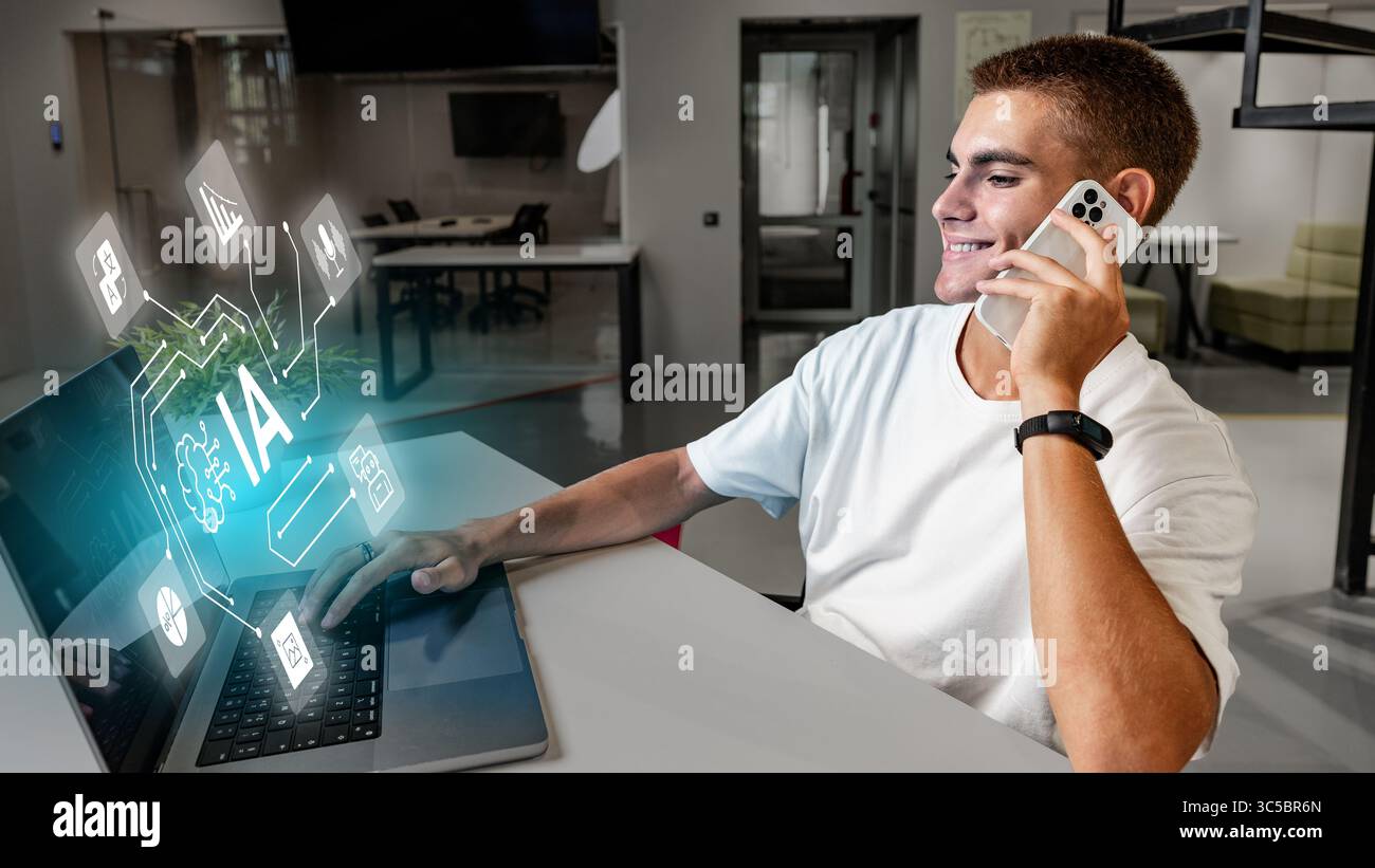 Young man engaged in technology work while talking on mobile device in modern office space Stock Photo