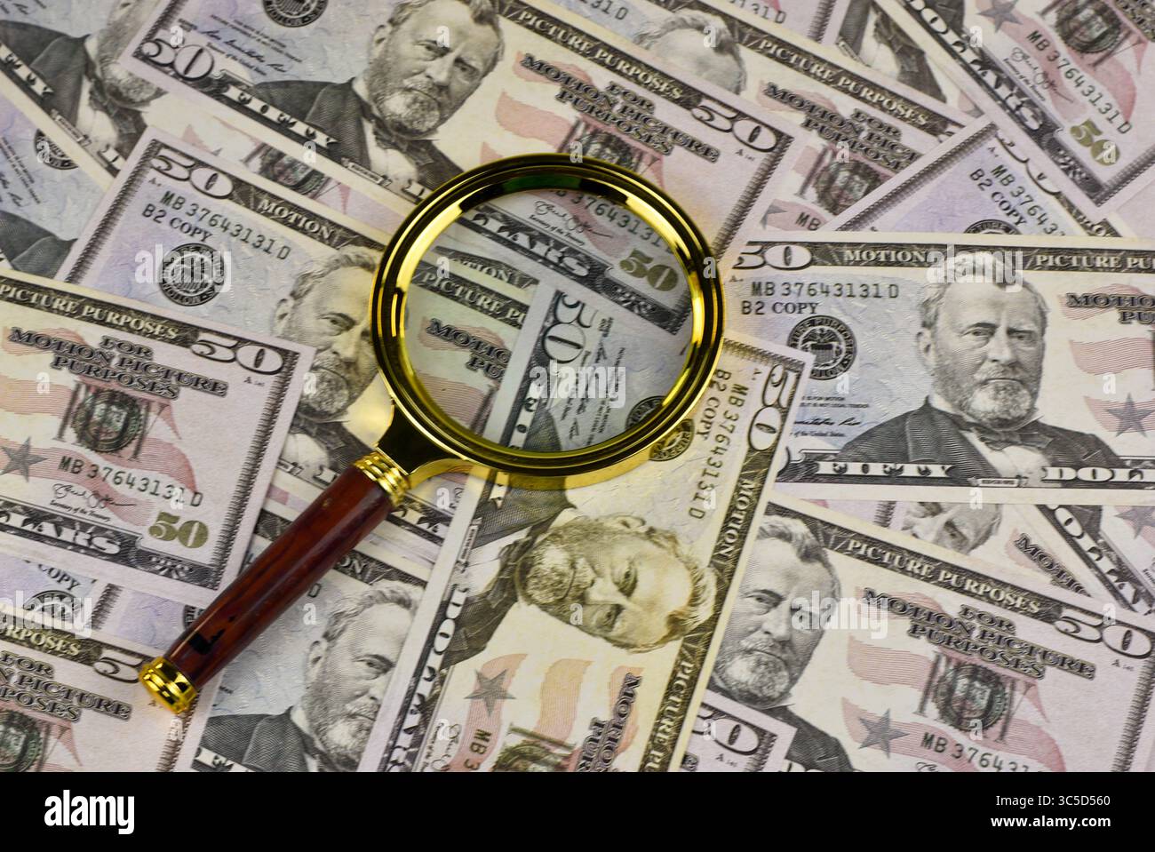 Magnifying glass focuses on the security features of a fifty-dollar ...