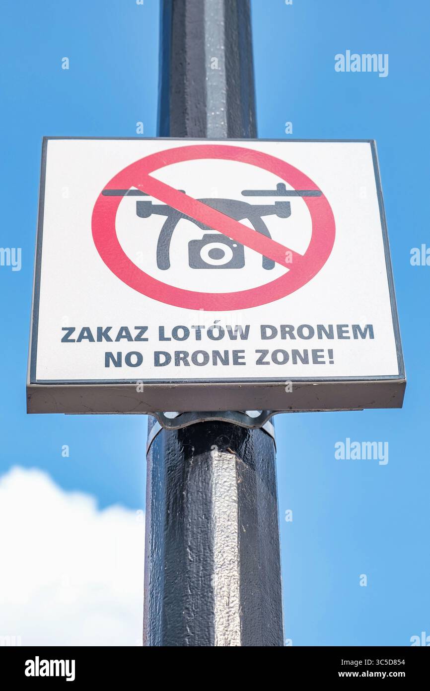 A "No Drone Zone" and "Zakaz Lotów Dronem" (Drone Flights Prohibited in Polish) sign on a pole, warning of a restricted airspace for UAVs. Stock Photo