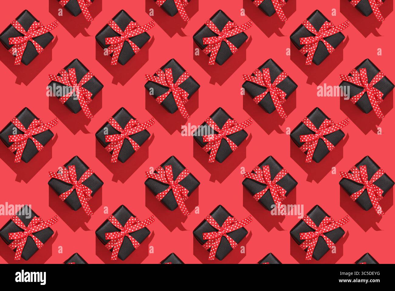 Pattern of black gift boxes with red bows on red background Stock Photo