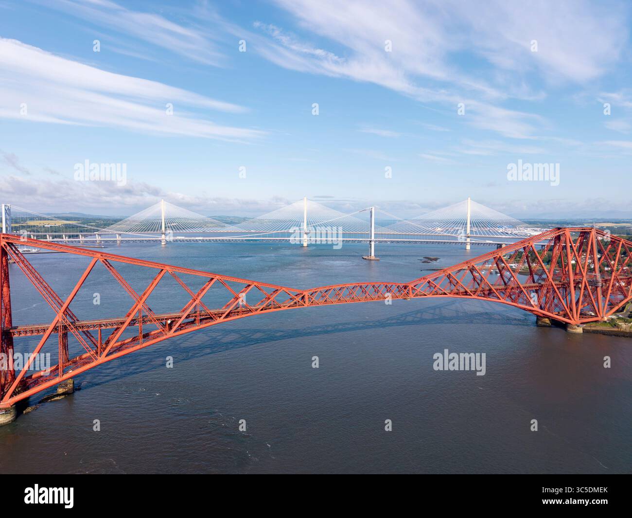 NORTH QUEENSFERRY, FIFE, SCOTLAND - JUNE 18, 2025: Firth of Forth showcasing the red cantilever Forth Rail Bridge alongside the cable‑stayed Queensfer Stock Photo
