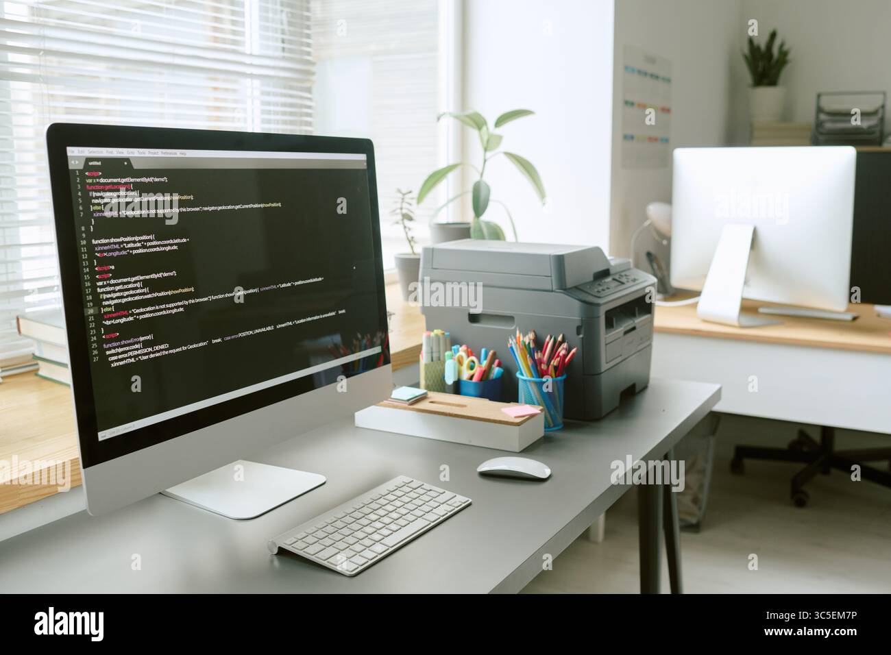 Modern Office Workspace Featuring Desktop Computer Displaying Programming Code Stock Photo