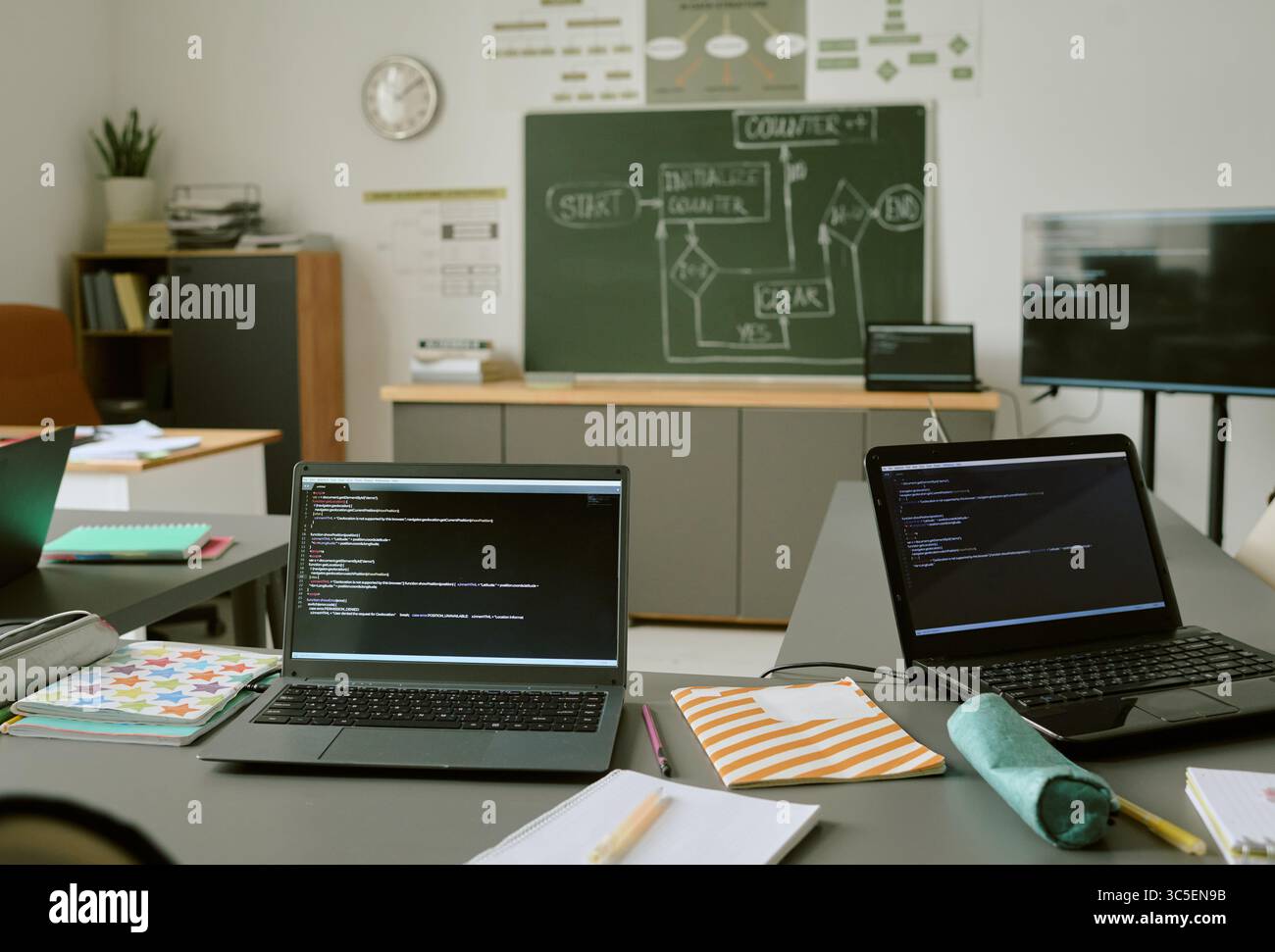 Two Laptops Displaying Programming Code in Classroom during Lesson Stock Photo