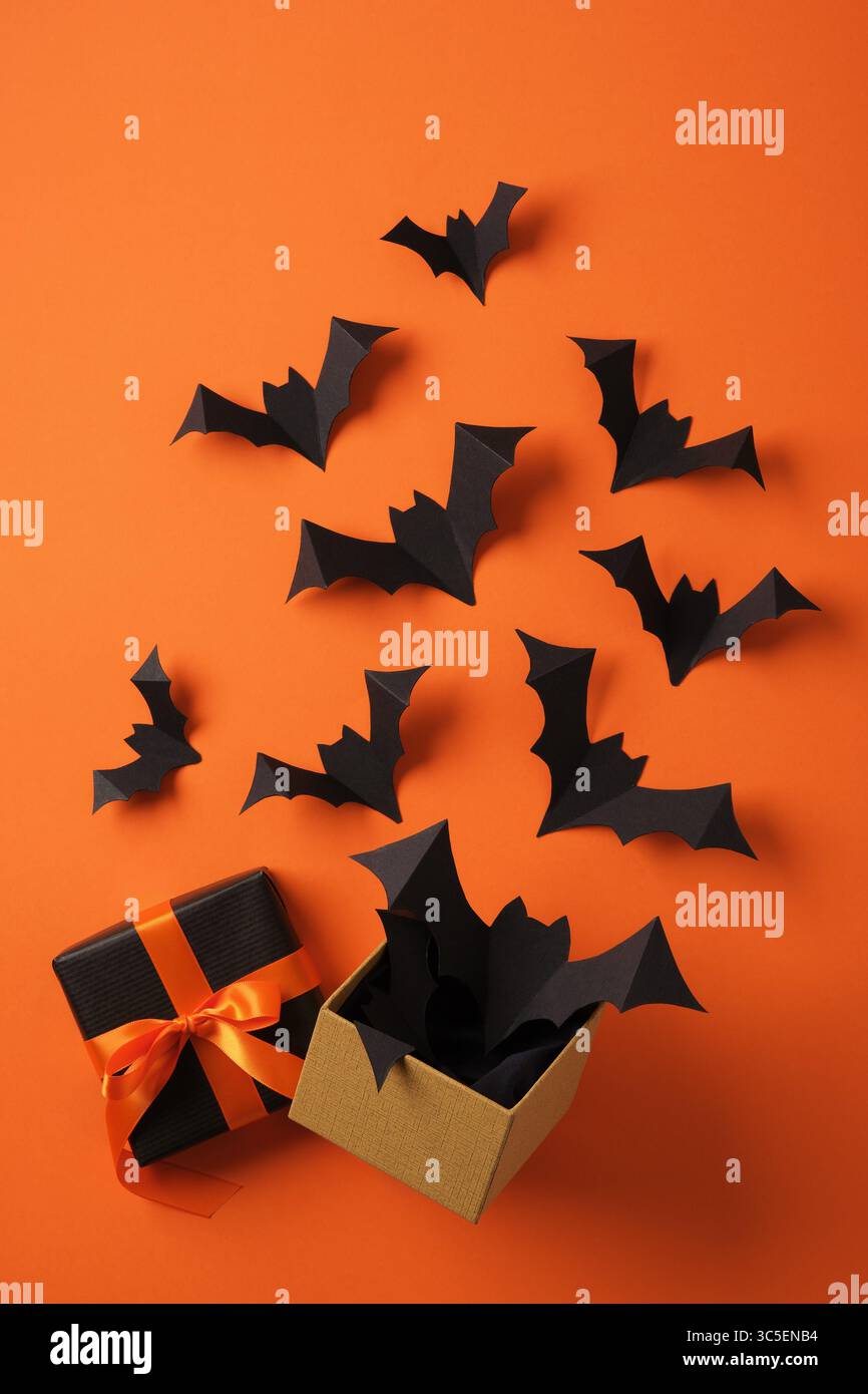 Paper bats flying out of gift box on orange backdrop. Background for ...