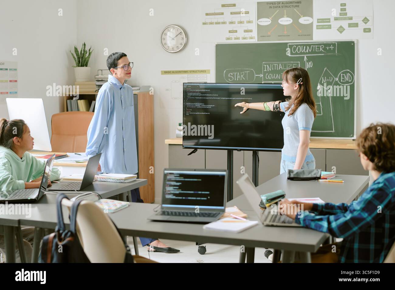 Diverse Teenagers Collaborating on Coding Project in Modern Classroom Setting Stock Photo