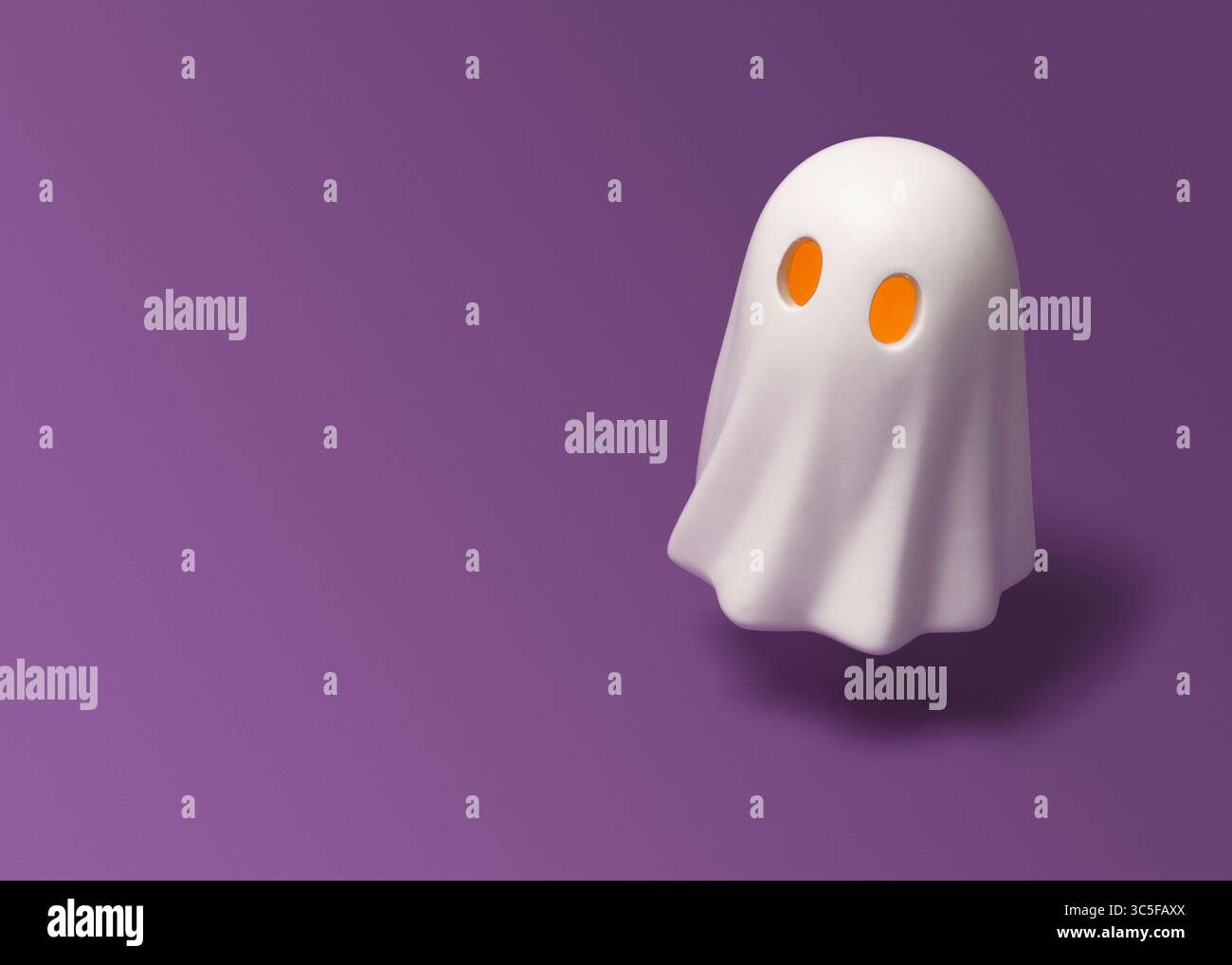 Halloween banner with ghost figurine with yellow eyes on purple background. Space for your text Stock Photo