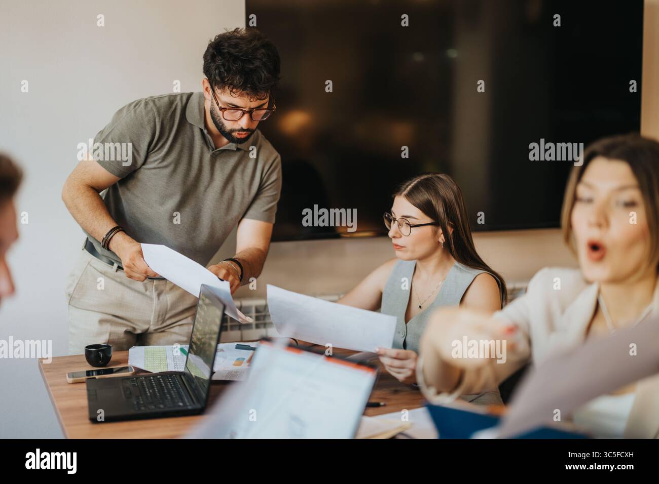 Team collaborating in an office setting on important paperwork and laptops Stock Photo