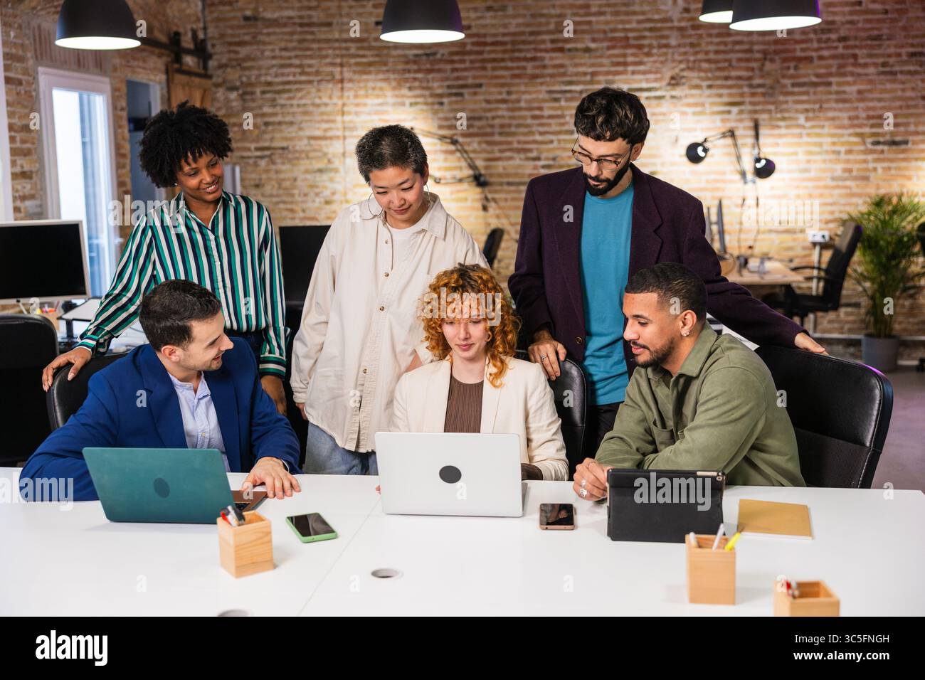 Multi ethnic team collaborating on project using laptop in modern office Stock Photo