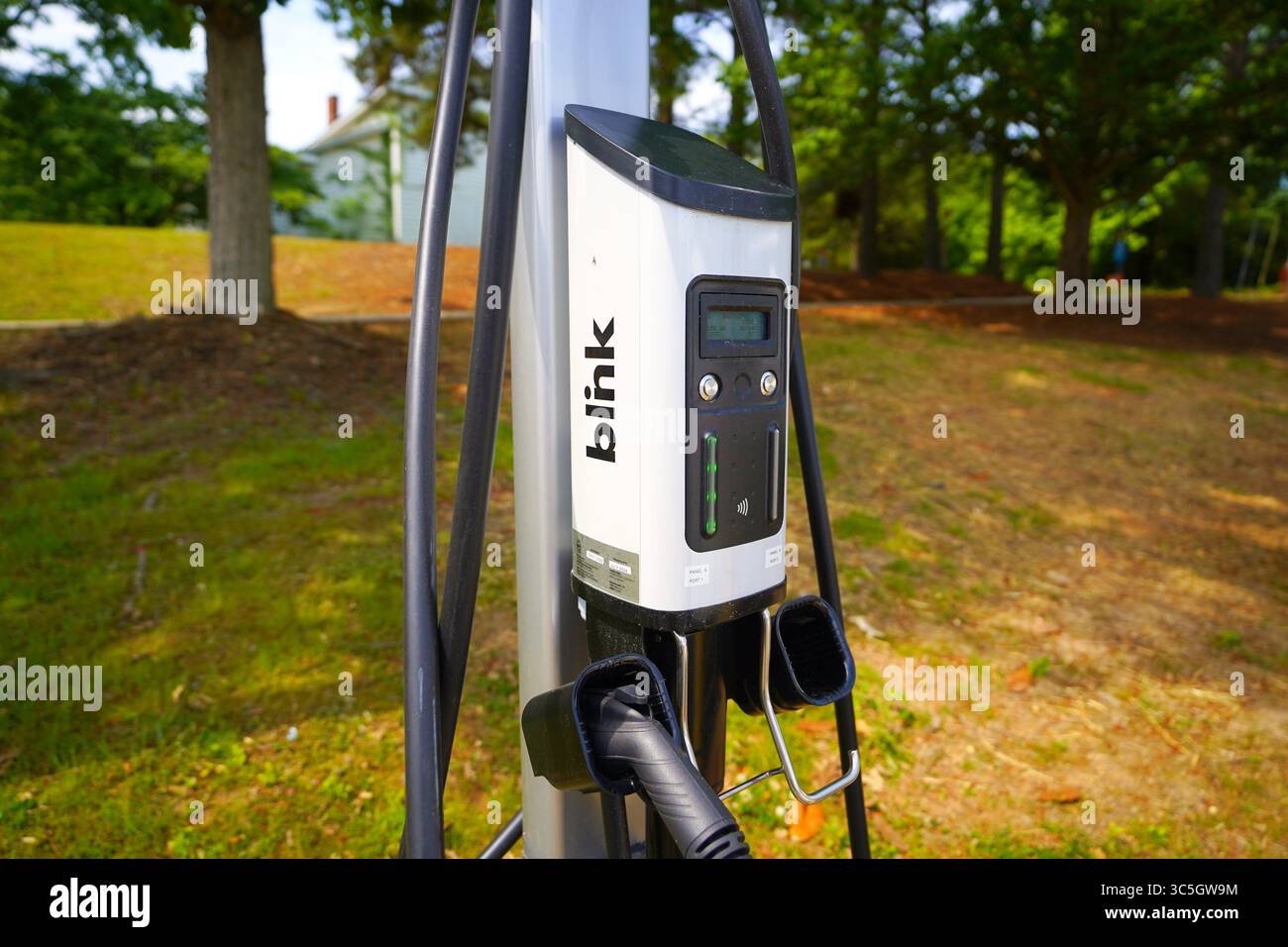 Blink EV Charger Station Installed In Parking Lot With Electric Vehicle Plugged In Stock Photo