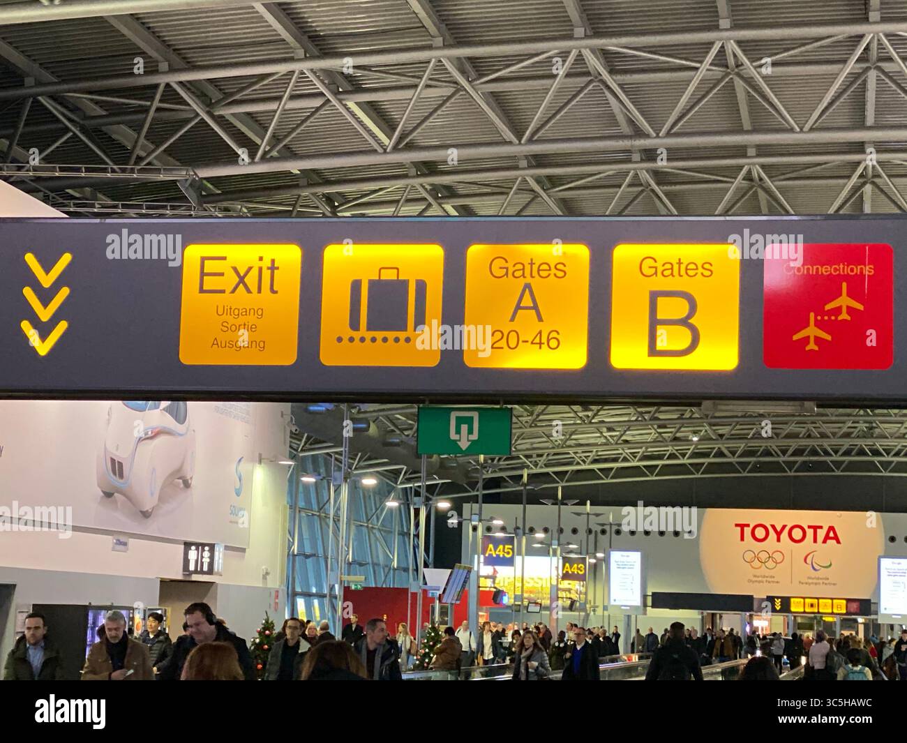 Brussels Airport. Belgium - Nov 18, 2019: Airport scene with directional signs including exit, gates, and connections above a crowd of people. - Smartphone Captured Stock Image