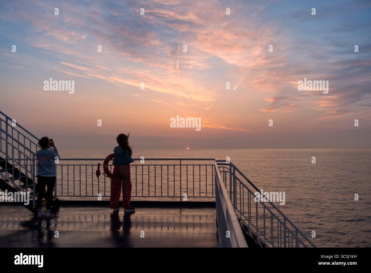 People contemplating the sunrise from a ferry deck.Near Barcelona.Spain Stock Photo