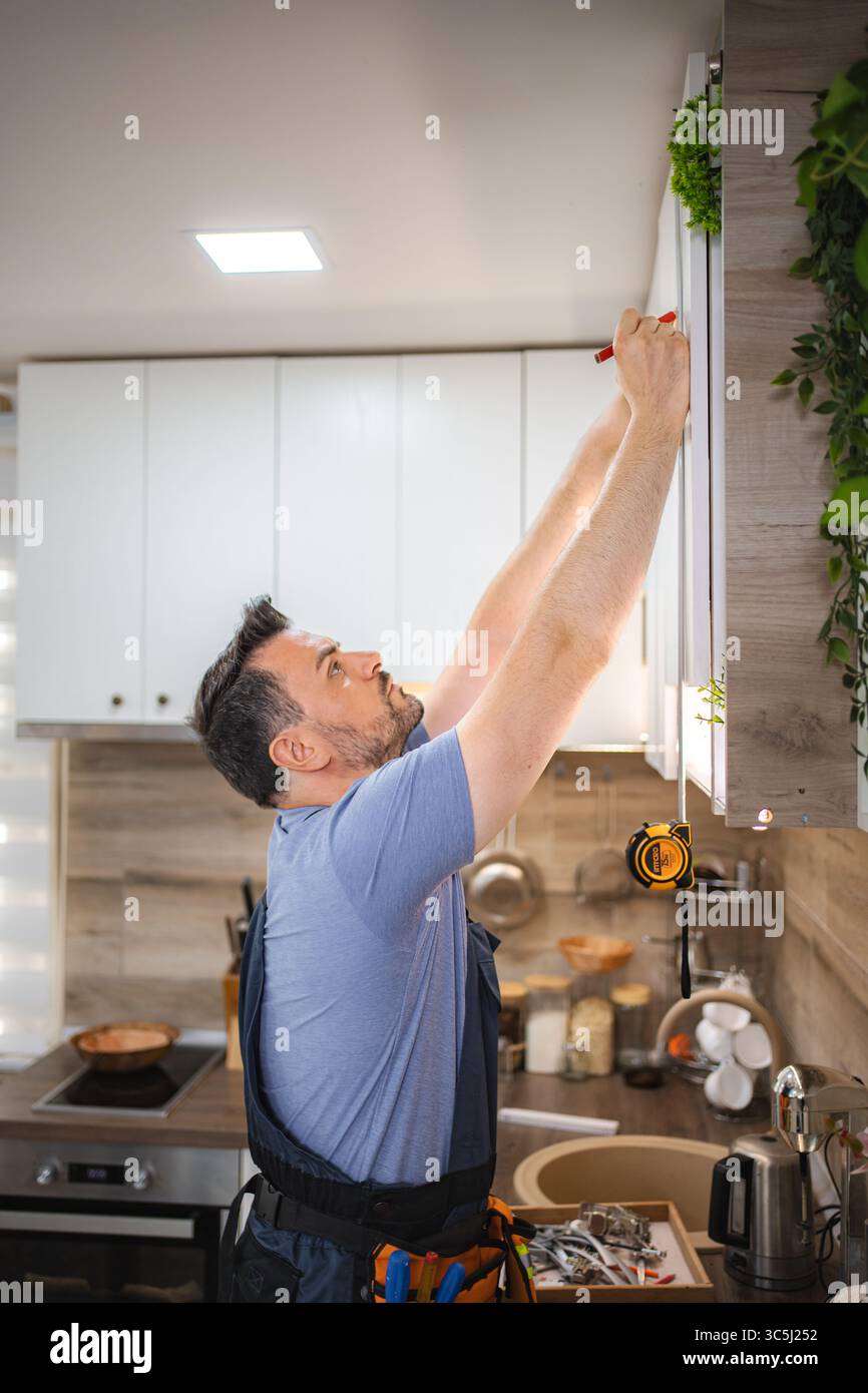 Carpenter working on a new kitchen furniture installation Stock Photo