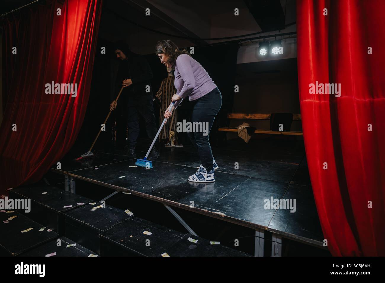 Actors cleaning the stage after a performance in a theatre setting ...