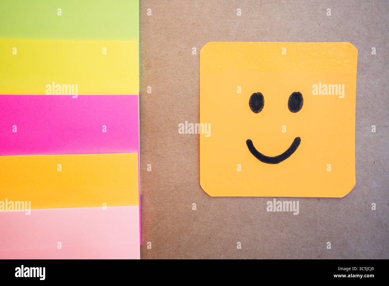 Happy face drawn on colored paper with black marker with a uniform solid background Stock Photo