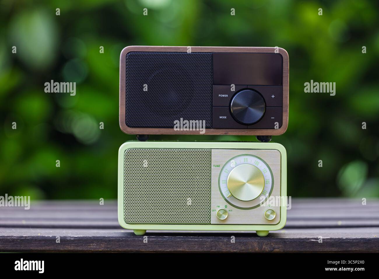 VINKOVCI, CROATIA, 06.13.2025:Retro and modern radios displayed outdoors, highlighting contrasting design elements on a wooden surface. Stock Photo
