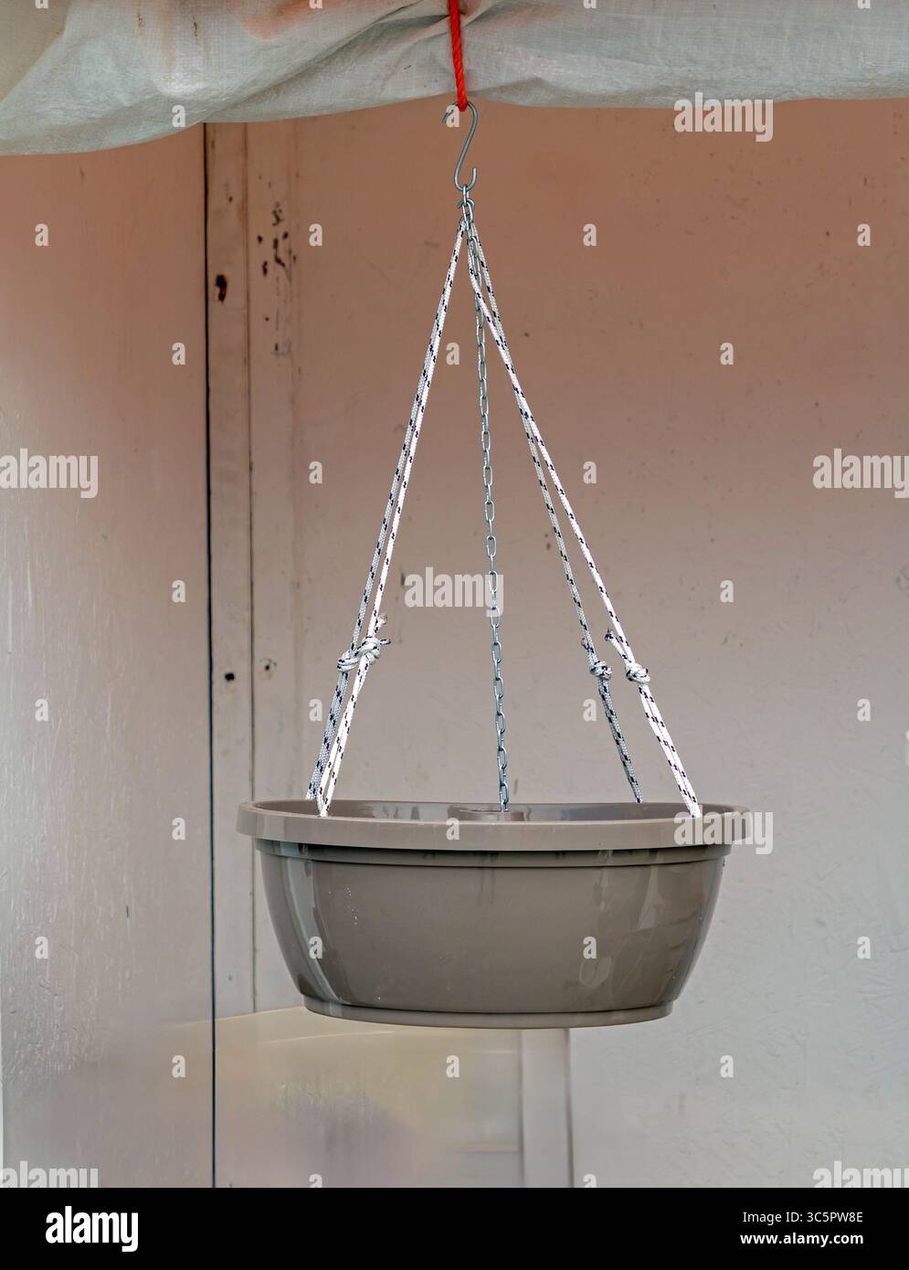 Empty plastic flower pot hanging from a ceiling Stock Photo